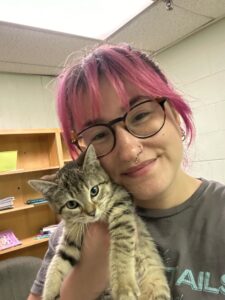 Woman with glasses and pink hair holding kitten