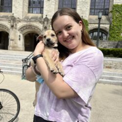 woman in pink shirt holding brown puppy